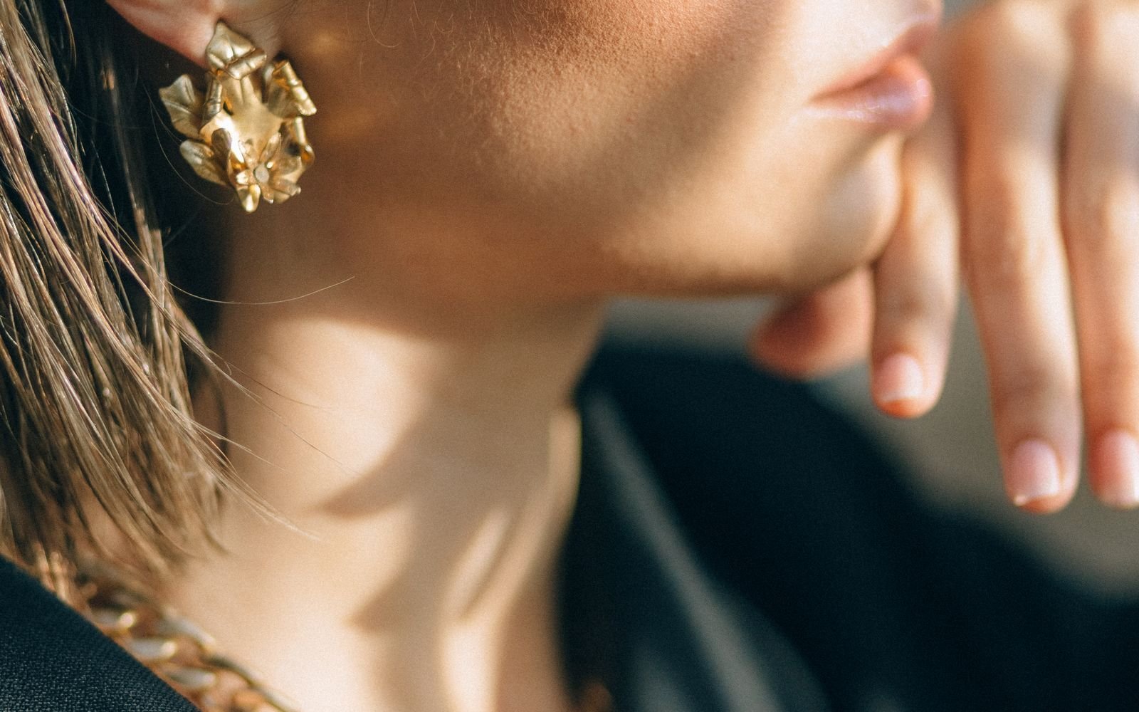 Close up of stacked ear piercings with multiple gold earrings