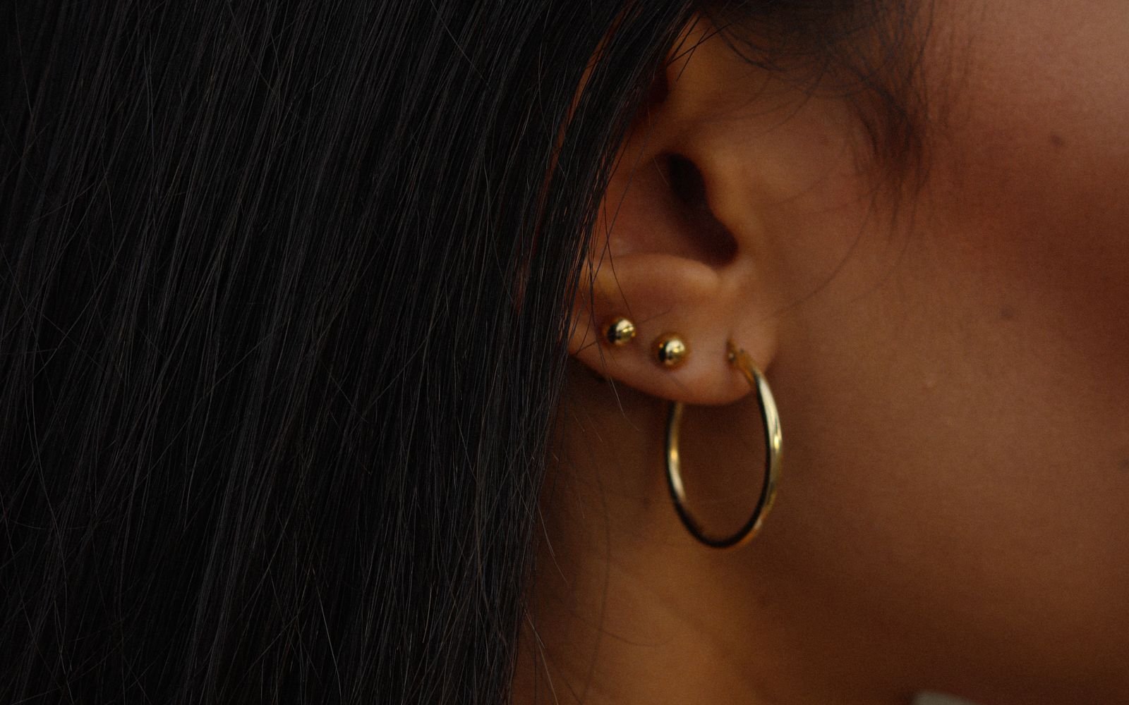 Close up of a woman wearing gold hoop and stud earrings