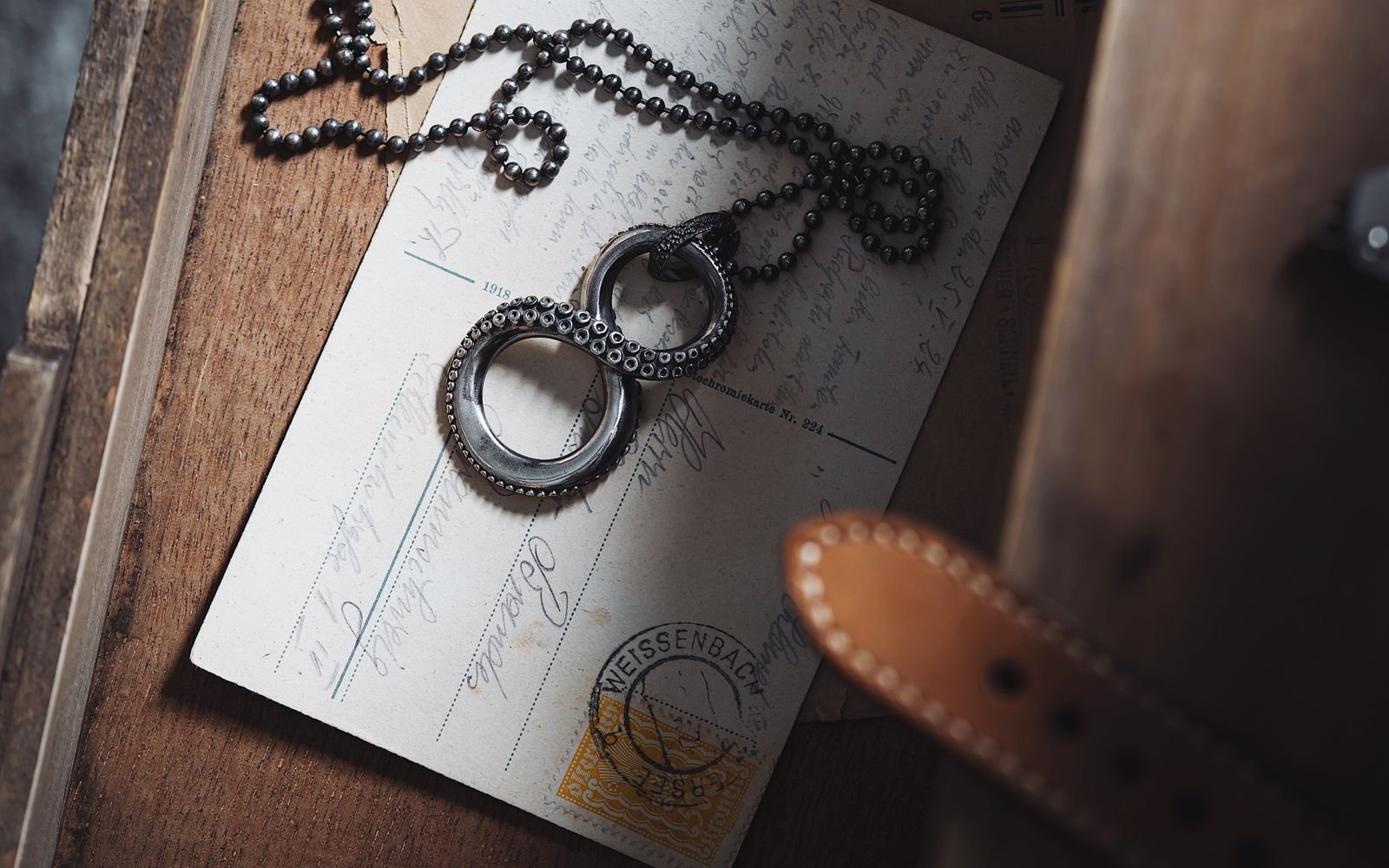 Vintage chain necklace placed on aged postcards in a wooden drawer